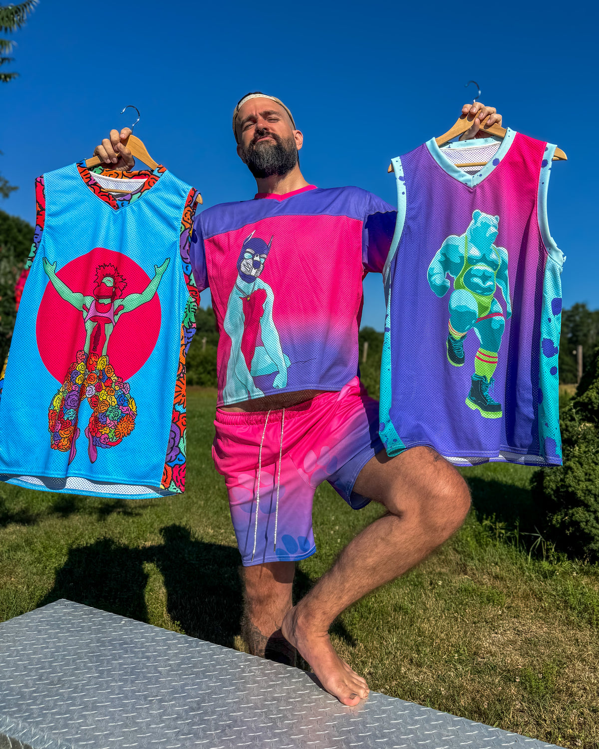 Smutpop outdoors, holding two jerseys featuring original artwork.